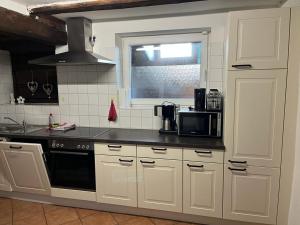 ÄuleRomantisches Schwarzwaldhaus的厨房配有白色橱柜和黑色台面