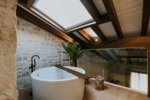 哈罗Puracepa - Urban Suites的带浴缸的浴室和天窗