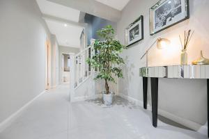 阿伯丁Countesswells Crescent Villa ✪ Grampian Lettings Ltd的白色走廊,有盆栽和桌子