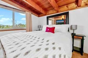 大熊湖Cozy Moon Cabin的卧室配有一张大白色床和红色枕头