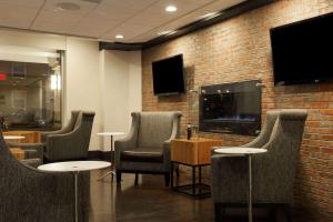 波士顿温德姆波士顿笔架山酒店的一间设有椅子和砖墙电视的等候室