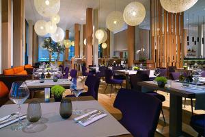 蒙彼利埃蒙彼利埃万怡酒店的餐厅设有桌子、紫色椅子和吊灯