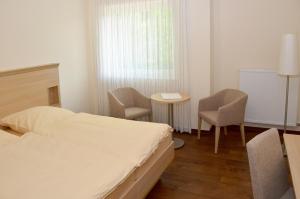 瓦伦霍尔斯特Gasthaus-Witte的一间卧室配有一张床、两把椅子和一张桌子