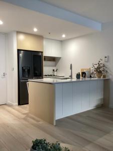 墨尔本In the Heart of Port Melbourne的厨房配有白色橱柜和黑色冰箱。