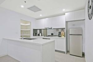 悉尼Aircabin｜Mascot｜Spacious & Modern｜Walk to station的白色的厨房配有白色橱柜和冰箱。