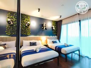 努沙再也Almas Suites by JBcity Home的一间有三张床的房间,墙上有植物