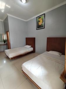 普禾加多Hotel Asri Baru的白色墙壁客房的两张床