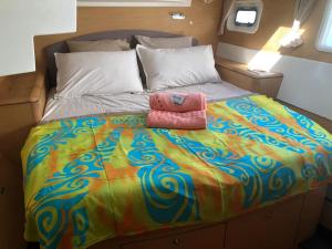乌图罗阿Catamaran Apetahi的一张大床,配有色彩缤纷的被子和两条粉红色的毛巾