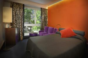 日内瓦新迷笛酒店的一间卧室配有一张床、紫色椅子和窗户