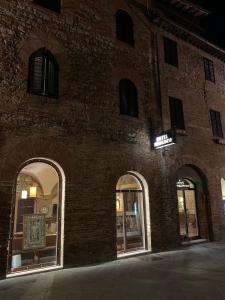 圣吉米纳诺美丽生活酒店的砖砌建筑,有拱形窗户和标志