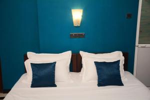 卡图纳耶克Ayubowan Homestay Katunayake的一张带蓝色墙壁和白色枕头的床