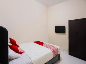 名古屋OYO 92451 Hasan House Syariah 2的一间卧室配有一张带红色枕头的床和一台电视。