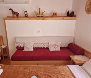 吉诺卡斯特Hotel Domino的一间卧室配有红色沙发,上面有枕头