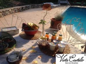 罗韦雷托Vista Castello的一张桌子,旁边是游泳池,摆放着食物和饮料