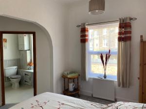 亨斯坦顿Crispin House的一间卧室设有一张床、一个窗口和一个卫生间