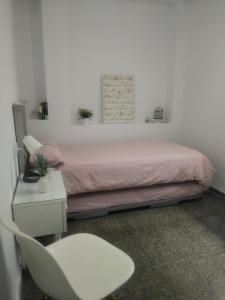 塞维利亚Sevilla Macarena apartamento 3 dormitorios的卧室配有粉红色的床和白色椅子