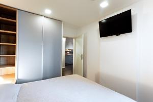 卢布尔雅那Elegant 1-bedroom apartment near hill forest的卧室配有白色的床和平面电视。