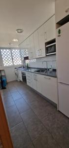 罗达德瓦拉Apto RODA BEACH的厨房配有白色橱柜和瓷砖地板。