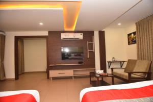 达尔瓦德M R Residency Dharwad.的一间配备有沙发及电视的酒店客房