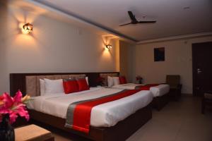 达尔瓦德M R Residency Dharwad.的两张位于酒店客房的床铺,配有红色枕头