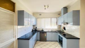 悉尼Carlton 3 beds unit - free parking的厨房配有白色橱柜和黑色台面