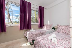 奥米什Apartments Villa White House的一间卧室设有两张床和一个带紫色窗帘的窗户。