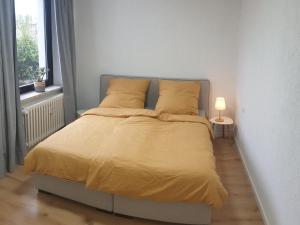 鲁尔河畔米尔海姆Studio Apartments in Ruhrgebiet的一间卧室配有一张带黄床单和一盏灯的床。