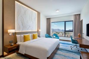 Jabal Al AkhdardusitD2 Naseem Resort, Jabal Akhdar, Oman的配有一张床、一张书桌和一扇窗户的酒店客房