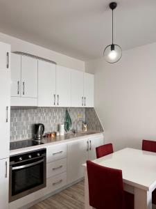 普里什蒂纳Cosy Apartment with a Great View的厨房配有白色橱柜和红色椅子的桌子