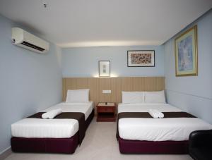 吉隆坡LA ISRA at KL的酒店客房带两张床,带白色和棕色的床单。