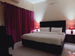 伊斯兰堡Travel Inn islamabad的一间卧室配有一张带红色窗帘的大床