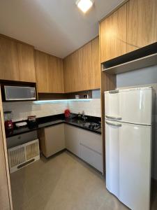 巴西利亚Flat em Brasília - Moderno e equipado的厨房配有白色冰箱和木制橱柜。
