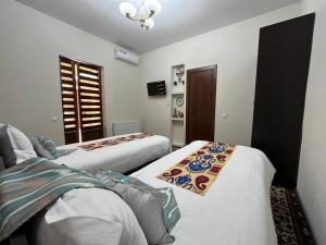 布哈拉OLD SAFARI HOTEL make yourself at home的酒店客房设有两张床和窗户。