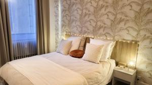 埃皮纳勒Appartement Cosy - En face de la gare, au centre ville的一间卧室配有一张带白色床单和壁纸的床。