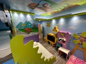 高雄高雄亲子溜滑梯High Fun旅店的儿童卧室,墙上挂着恐龙壁画