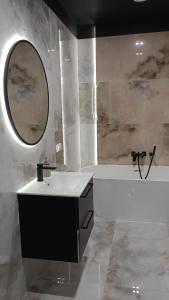 罗兹Manu Park Apartament z Garażem Centrum的一间带水槽、浴缸和镜子的浴室