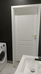 罗兹Manu Park Apartament z Garażem Centrum的一间带洗衣机和白色门的浴室