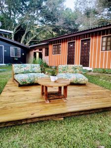蜜岛Pousada Recanto das Cores的木制甲板配有两张沙发和一张桌子