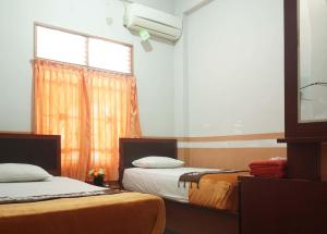 BangkinangHotel Al Madinah Bangkinang的客房设有两张床和窗户。
