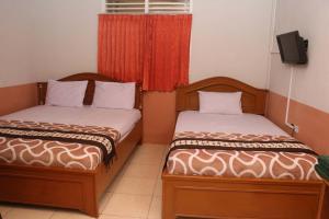 BangkinangHotel Al Madinah Bangkinang的两张睡床彼此相邻,位于一个房间里