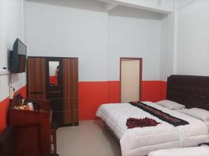 BangkinangHotel Al Madinah Bangkinang的一间卧室配有两张床和电视。