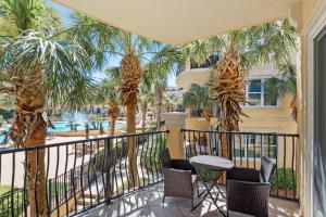 蓝湾海滩Adagio F205的一个带棕榈树和桌椅的阳台