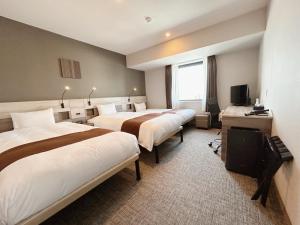 函馆Smile Hotel Premium Hakodate Goryokaku的酒店客房设有两张床和电视。
