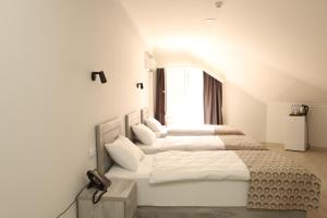 阿哈尔齐赫Aventus Hotel的白色卧室设有四张床和窗户