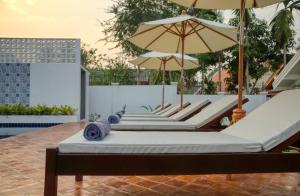 琅勃拉邦Chic stay HANA Boutique hotel的庭院里摆放着一排带遮阳伞的躺椅