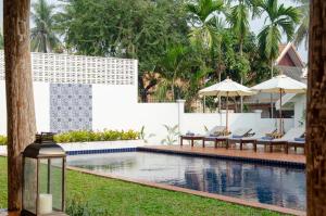 琅勃拉邦Chic stay HANA Boutique hotel的度假村的游泳池,配有椅子和遮阳伞