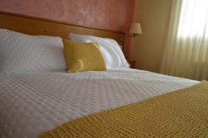 Antas de UllaHotel Restaurante Val的一张配有白色床单和黄色枕头的大床