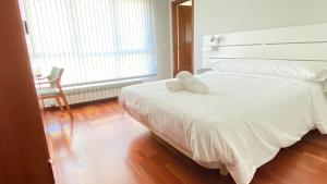 费雷拉Apartamentos Pantón Ribeira Sacra的卧室内的一张带两个枕头的白色床