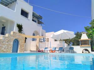 皮索利瓦迪Villa Danae - Seaside Villa with Pool & Hot Tub的一座带遮阳伞和椅子的游泳池以及一座建筑