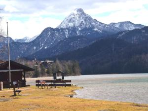 福森Holiday home in Füssen with garden的山 ⁇ ,坐在水体旁